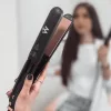 Nő kezében a Magic Steaming Iron hajvasaló, mögötte hosszú kivasalt haj